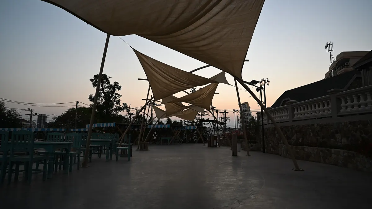 Terrasse vide au crépuscule, sous des voiles d'ombrage