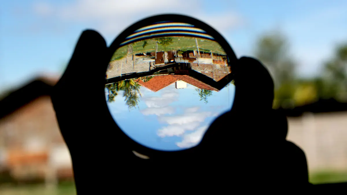 Une boule de verre tenue à contre-jour renvoie un paysage à l'envers