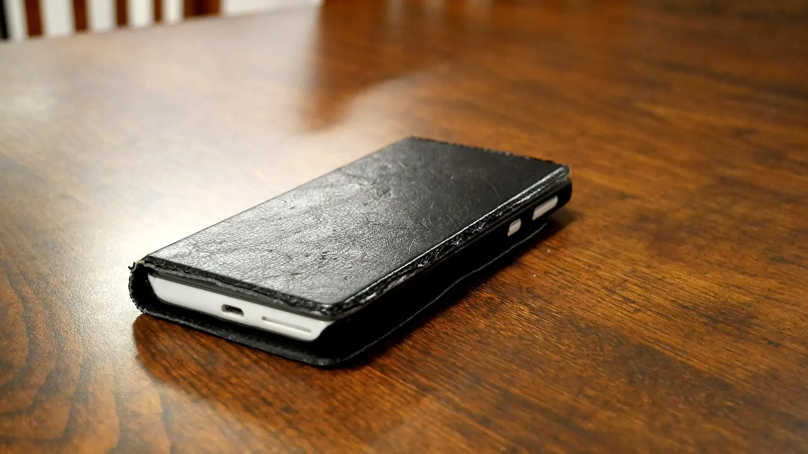 Smartphone dans un étui en cuir posé sur une table en bois
