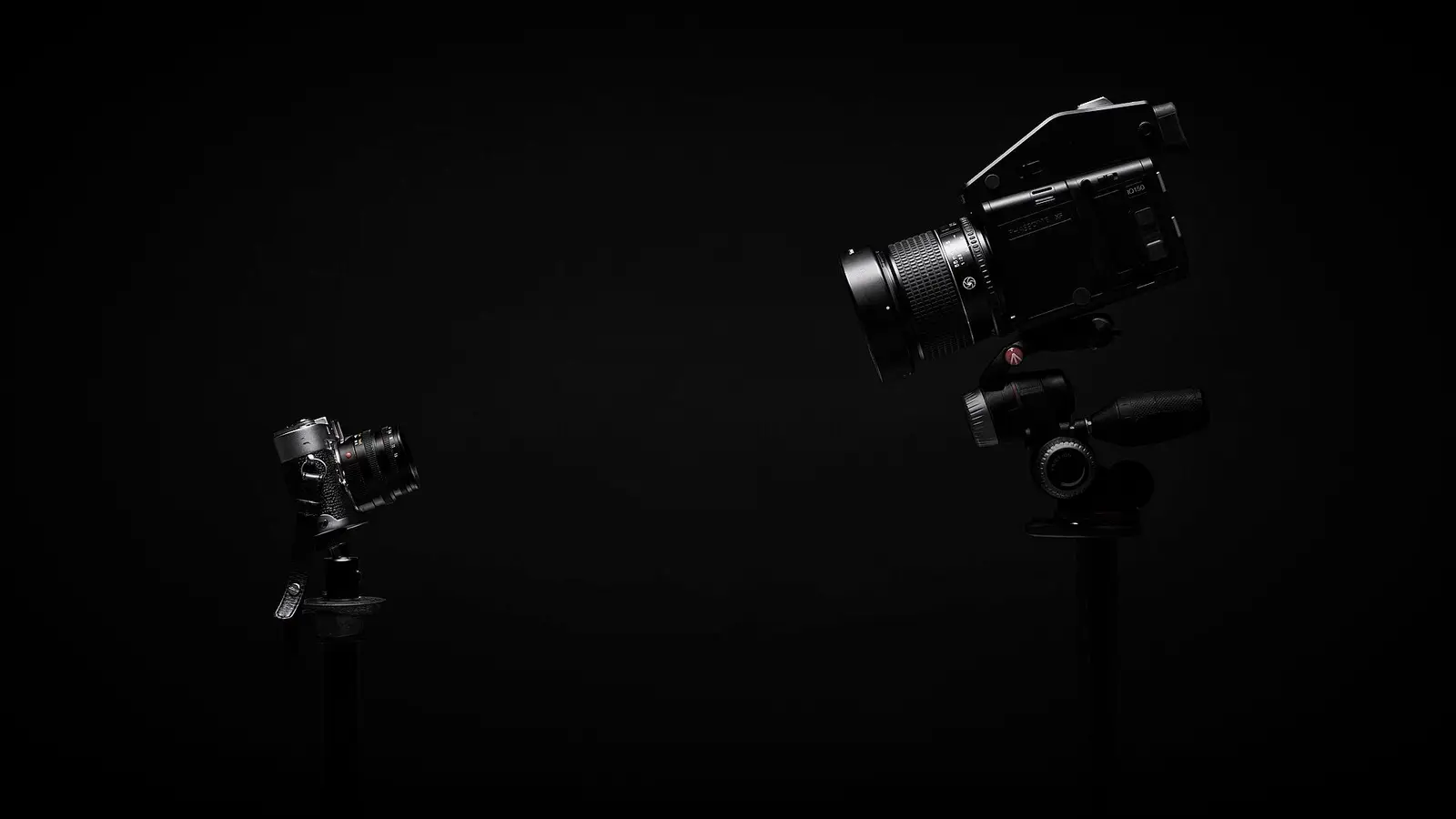 Un appareil photo et une caméra sur trépied dans un studio sombre