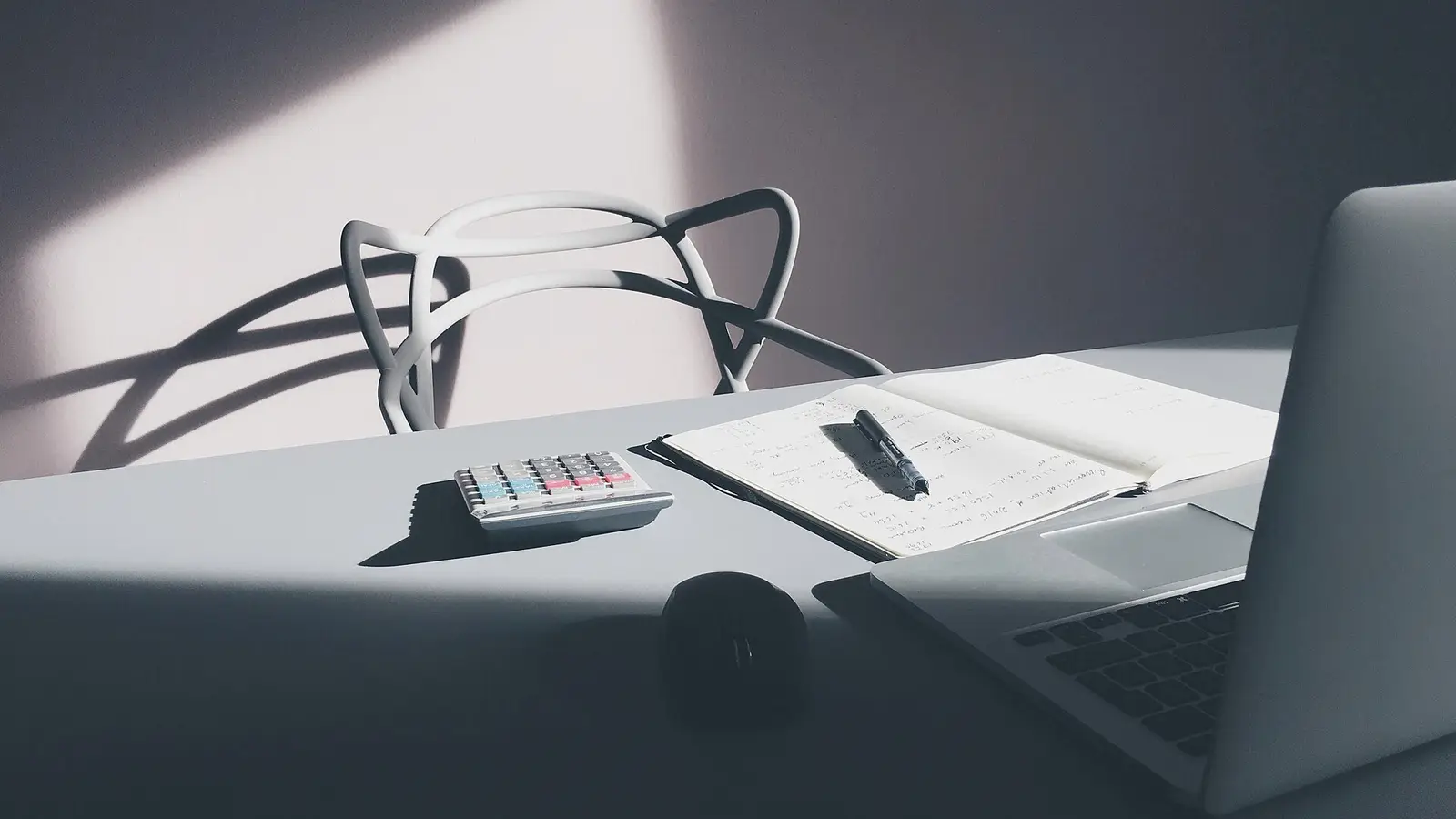 Bureau avec une calculatrice, un carnet de notes et un ordinateur portable