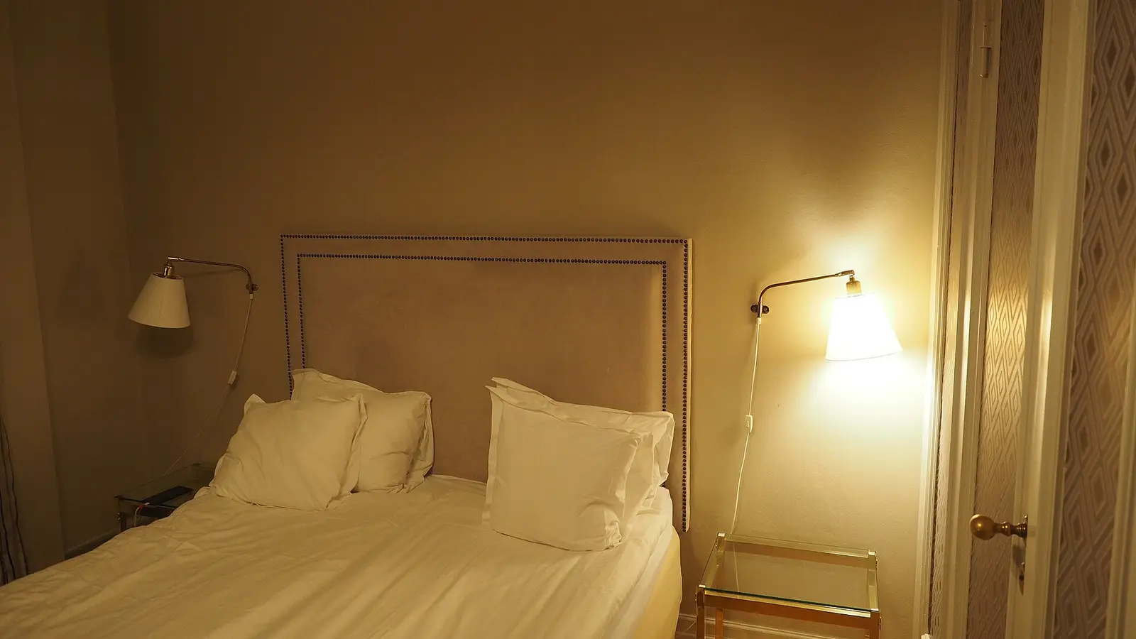 Lit double d'une chambre d'hôtel, appliques allumées